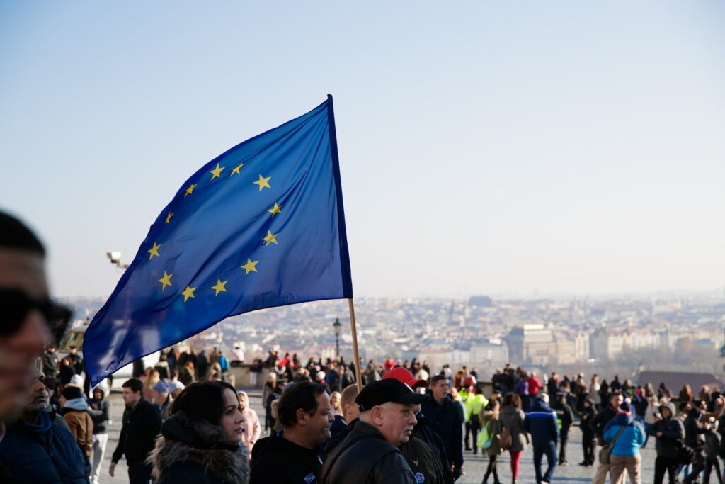 Un groupe de personnes brandissant un drapeau de l’UE devant un bâtiment présentant des techniques de recrutement innovantes.