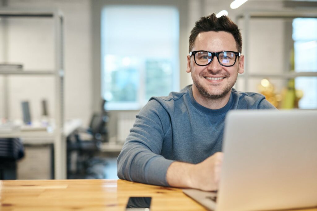 Un candidat portant des lunettes est assis à un bureau avec un ordinateur portable et acquiert de l'expérience.