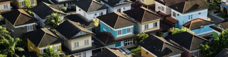 Vue aérienne d'un quartier résidentiel composé de plusieurs maisons aux toits sombres, aux extérieurs colorés et entourées de verdure - idéal pour les personnes à la recherche d'un emploi dans les environs. Photo concernant l'utilisation d'un logiciel ATS de recrutement dans l'immobilier pour améliorer l'expérience candidat